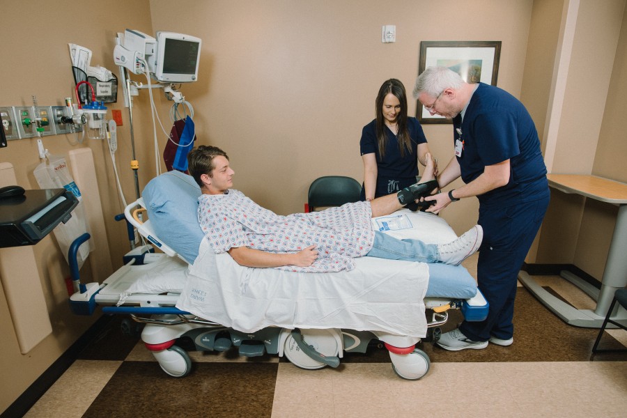 Doctor and nurse examining male patient's foot in brace